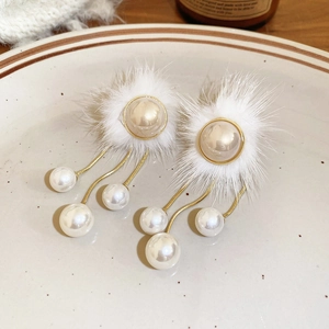 Detail view of winter fur ball earrings with pearl tassels and gold metal chain