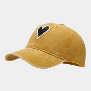 Detail of vintage washed mustard cotton baseball cap featuring a heart embroidery patch