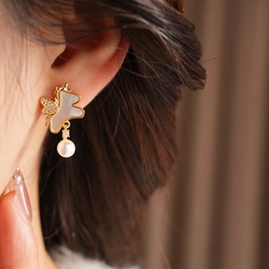 Gros plan d'une boucle d'oreille papillon en or 18 carats avec nacre, zircon et perle