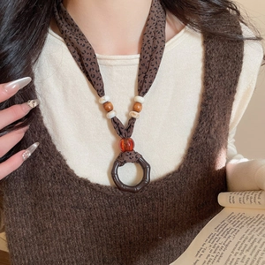 Detail of fabric beaded necklace with leopard print strap and amber resin pendant