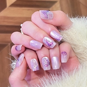 Close-up of lilac cat eye press-on nails with white wave and mermaid tail patterns