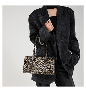 Leopard print baguette bag with dual handles shown on model wearing a black blazer