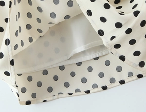 Close-up of beige polka dot chiffon dress hemline featuring a white inner lining