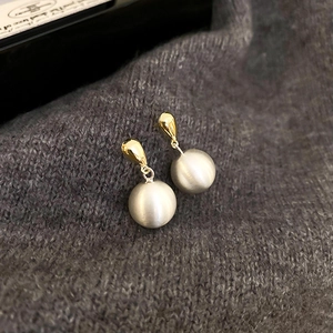 Détail de crochets dorés avec perles argentées mates sur maille grise texturée