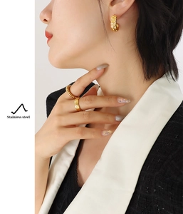 Detailed shot of gold-plated stainless steel C-shaped earrings and quilted pattern rings