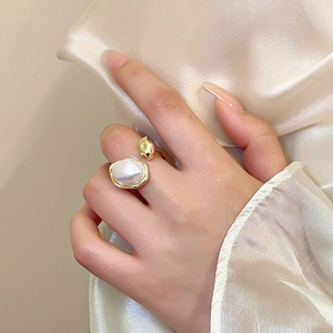Detail of vintage gold-plated open ring featuring an irregular white pearl on a silk background