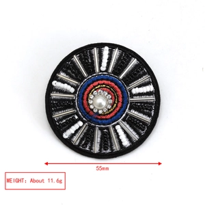 Detailed view of handmade embroidered evil eye brooch with crystals and beads