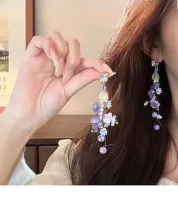Detail of long purple floral tassel earrings with pearls and crystal on a model