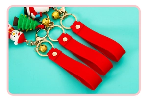 Macro detail of Christmas soft rubber keychains featuring Santa and golden metal bells