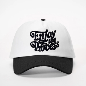 Detailed close-up of the black Enjoy the Process embroidery on white cotton baseball cap