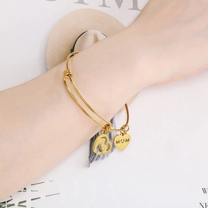 Close-up of golden adjustable heart bracelet with MOM engraving and pearl details