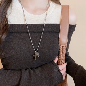Detail of vintage stainless steel necklace with brown stone cross and metal charms