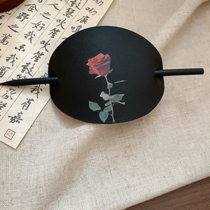 Nahaufnahme einer chinesischen Leder-Haarnadel mit elegantem rotem Rosendruck auf schwarzer Basis
