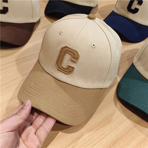 Detail of color-block baseball caps with embroidered C patch on a wooden surface