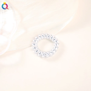 Macro shot of a clear spiral hair tie with a glossy finish on a minimalist background