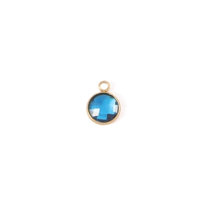 Close-up of a 7mm round gold-plated birthstone pendant with faceted dark blue crystal