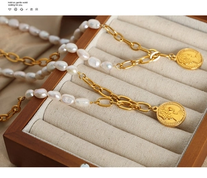 Detail of freshwater pearl necklace with gold relief coin pendant in jewelry box