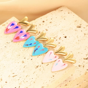 Close-up of heart-shaped enamel drop earrings in pink and blue on stone texture