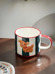 Detail of hand-painted dog ceramic mug with black stripes and red accents on wood surface