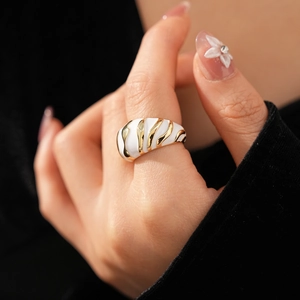 Close-up of vintage enamel dome ring with gold textured stripes on a model's finger