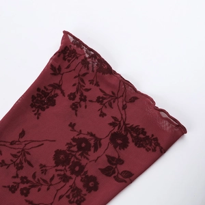 Détail de maille rouge foncé avec flocage floral noir et bordure ondulée douce