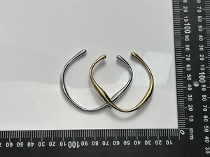 Detailed view of irregular C-shaped stainless steel bracelets in gold and silver finish