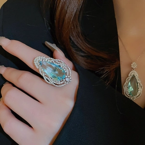 Close-up of luxury set featuring teardrop blue gemstone pendant and matching ring on model