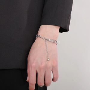 Detail of silver double-layer link chain bracelet with small round pendant on wrist