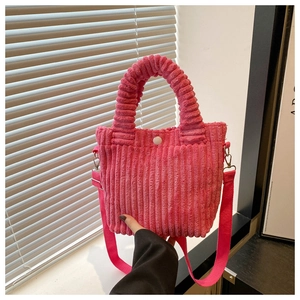 Detail of pink corduroy handbag showing soft fabric texture and woven handles