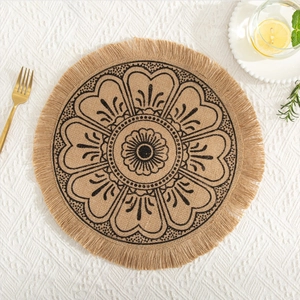 Detail of round jute placemat with black mandala print and fringe on white tablecloth
