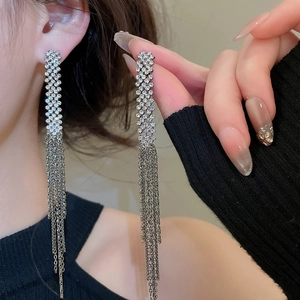 Silver long tassel earrings with sparkling rhinestones worn by a model in a close-up view