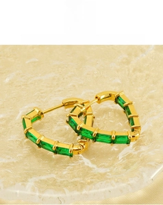 Close-up of gold heart hoop earrings with rectangular emerald zircon stones in high detail
