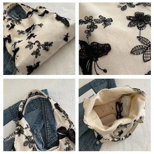 Detail of white canvas tote bag showing butterfly flower embroidery and large interior space
