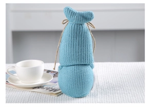 Detail of blue knitted gnome decor with twine bow on a cozy white textured tablecloth