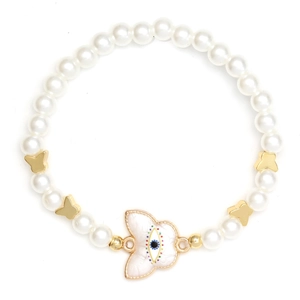 Detailed view of white faux pearl bracelet with gold butterfly charms and evil eye pendant