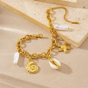 Gold stainless steel ocean bracelet with starfish conch and white pearls on beach sand