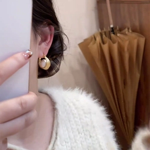 Gros plan de créoles plaquées or 16 carats avec perle ronde portées par un mannequin