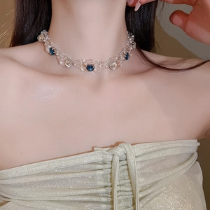 Close-up of beaded crystal necklace with dark blue heart charms on model's neck