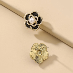 Vintage black floral stud earrings with white pearls and gold metal back on beige leather