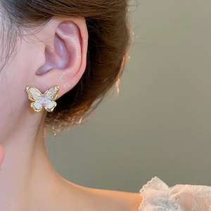 Close-up of butterfly stud earring in 18k gold plating with lavender zircon and white enamel