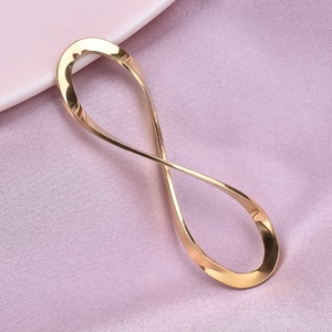 Macro shot of gold infinity symbol pendant on soft pink silk background