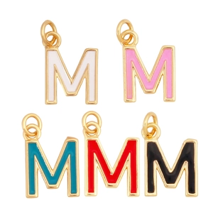 Detail of five colorful enamel letter M charms with gold metal frames on a white background