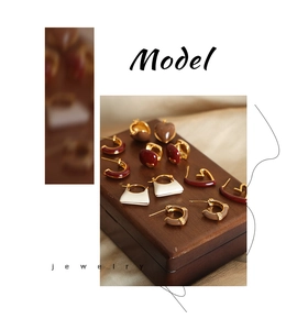Detailed close-up of vintage colorful enamel earrings with gold plating on a wooden display