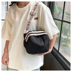 Detail of waterproof black nylon crossbody bag with ethnic style woven shoulder strap
