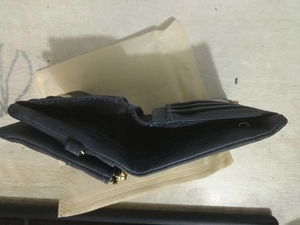 Detail view of a dark blue folded leather wallet showing internal card slots and dust bag