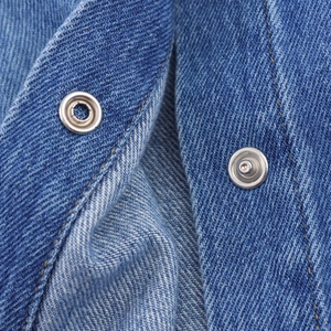 Nahaufnahme von silbernen Metallknöpfen und gelben Nähten auf blauem Denim-Gewebe