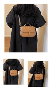 Detail view of a tan pebble leather crossbody bag with elegant gold buckle and strap