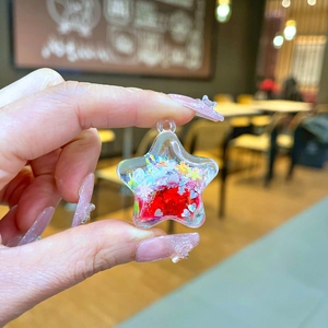 Detail of star-shaped crystal charm with red heart core and colorful glitters