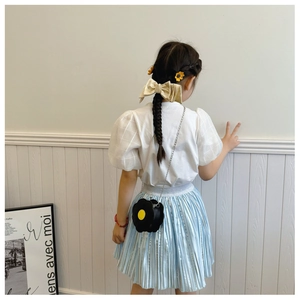 Detail view of a black sunflower-shaped shoulder bag on a little girl outfit