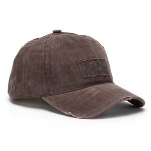 Detail of frayed edges and COQUEST embroidery on washed dark brown cotton baseball cap